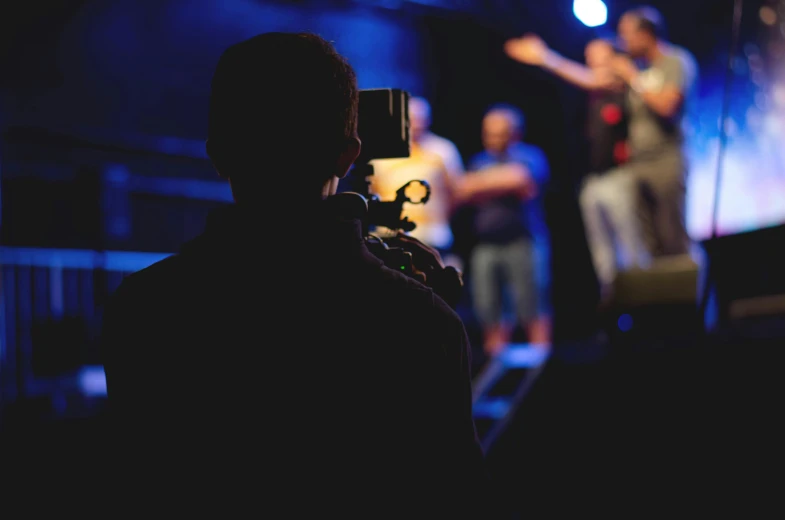 a person taking a picture of a band on stage, pexels contest winner, happening, cctv footage of a movie set, tabernacle deep focus, looking across the shoulder, standup comedian