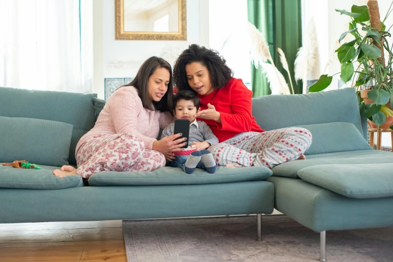 a couple of women sitting on top of a blue couch, pexels, portrait of family of three, red sweater and gray pants, checking her phone, avatar image