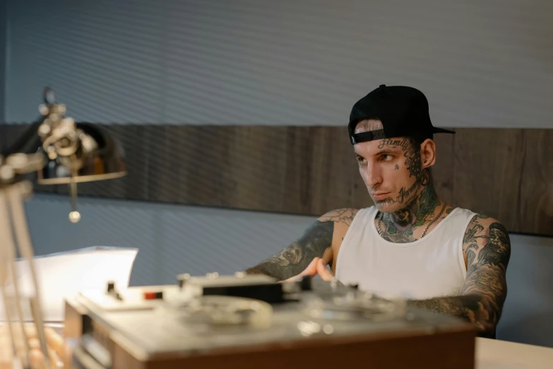 a man sitting at a desk in front of a laptop computer, a tattoo, inspired by Seb McKinnon, turntables, profile image, profile picture 1024px, looking serious