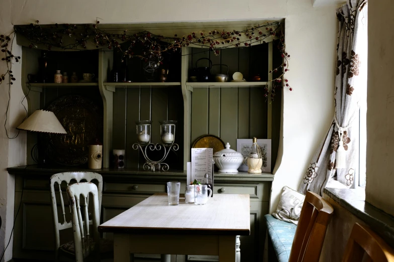 a table and some chairs in a room, by Sylvia Wishart, unsplash, a quaint, at the counter, cosy, green