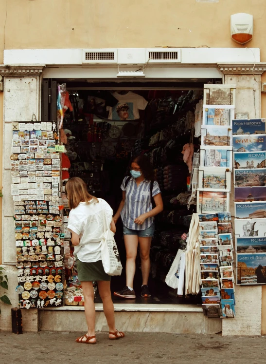 a couple of women standing in front of a store, a picture, running through italian town, profile image, scrapbook, 🚿🗝📝