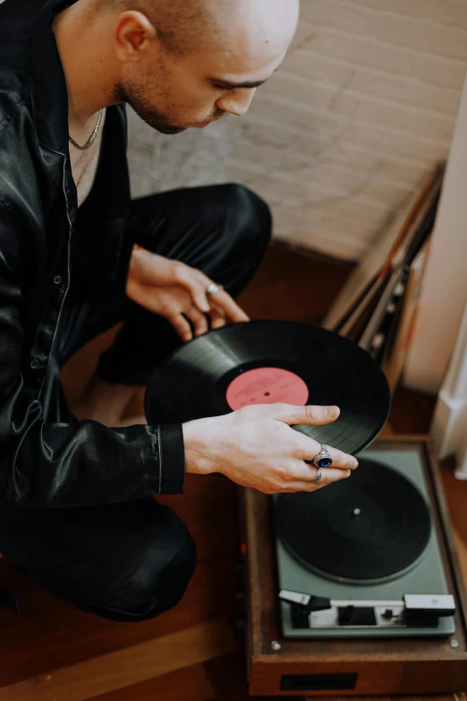 a man sitting on the floor next to a record player, trending on pexels, a man wearing a black jacket, inspect in inventory image, soft vinyl, spinning hands and feet