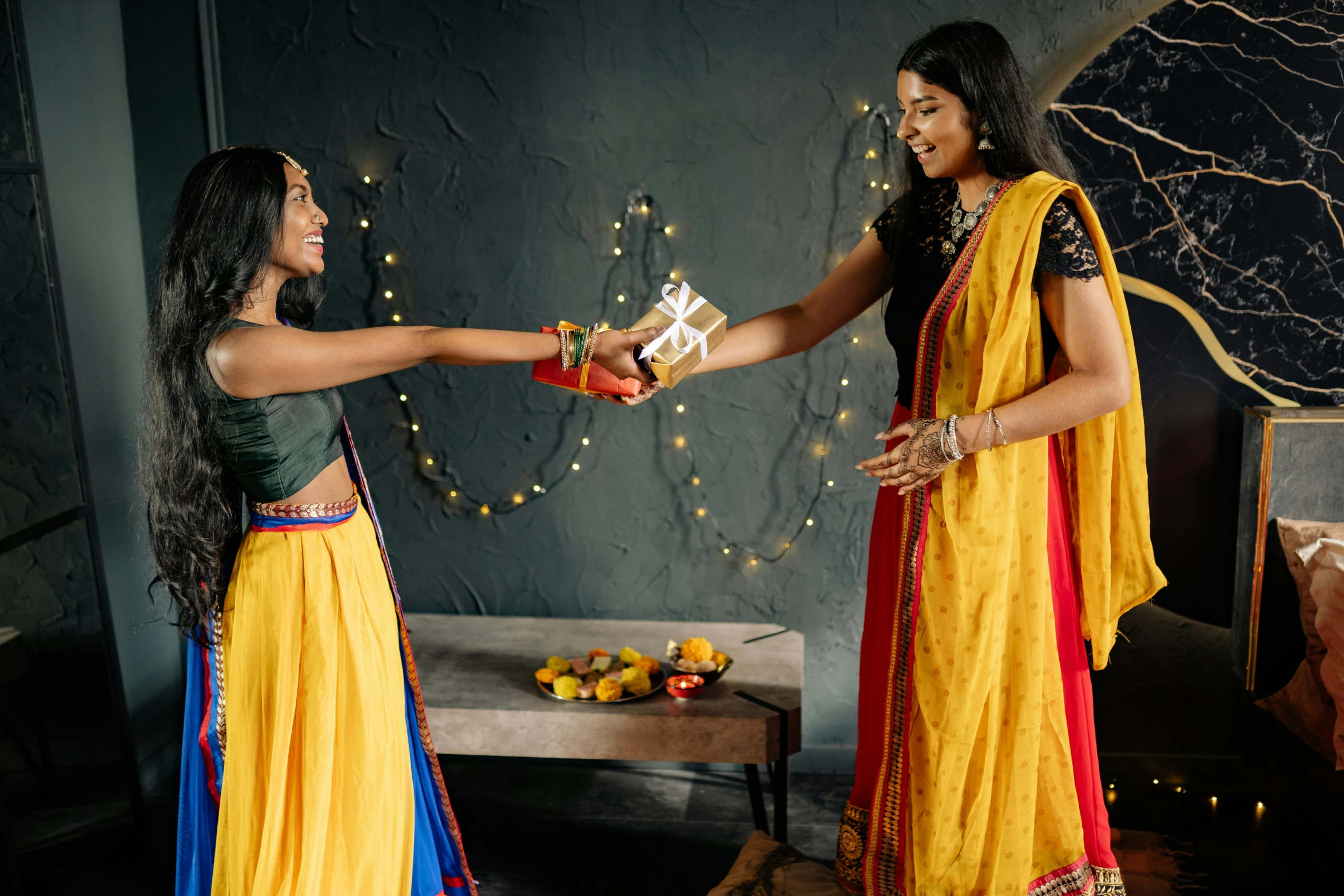 a couple of women standing next to each other, pexels contest winner, hurufiyya, giving gifts to people, hindu aesthetic, yellow and blue ribbons, avatar image