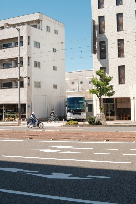 a man riding a bike down a street next to tall buildings, shin hanga, buses, けもの, residential area, rectangle