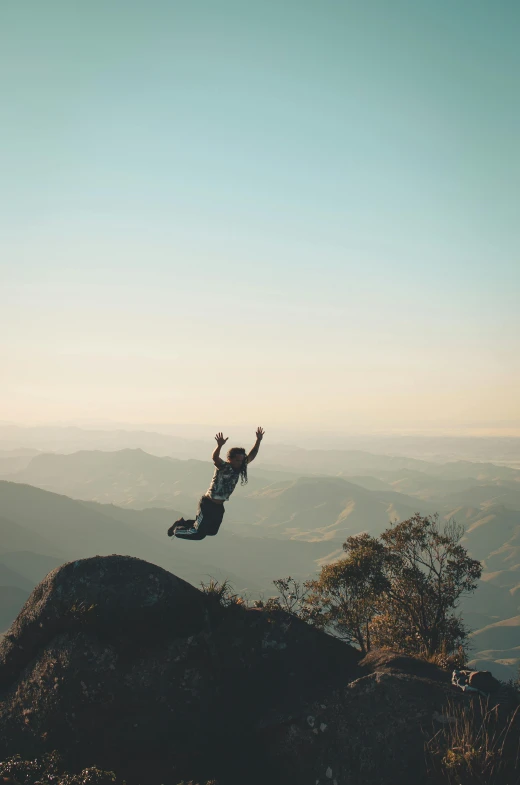 a person jumping in the air on top of a mountain, pexels contest winner, point break, octane--8k, head down, natural morning light