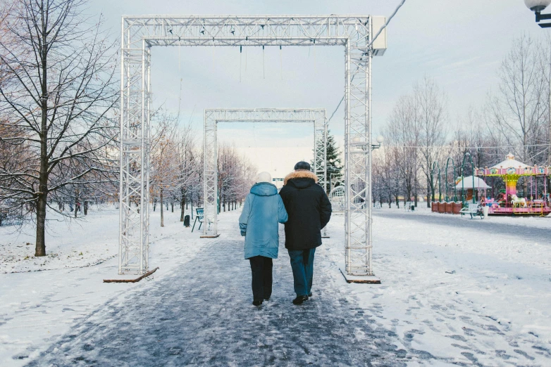 a couple of people that are walking in the snow, by Jaakko Mattila, pexels contest winner, visual art, archway, festivals, soviet style, in a city park