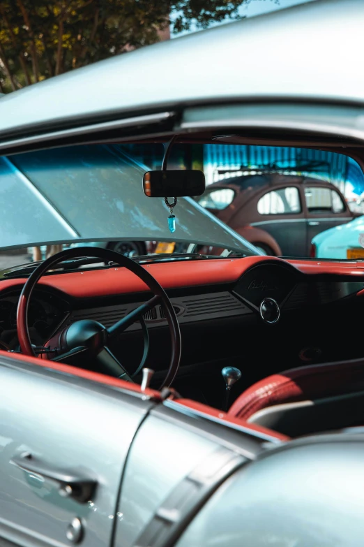 a man sitting in the driver's seat of a car, by Tom Bonson, pexels contest winner, retrofuturism, gleaming silver and rich colors, square, cars parked, inspect in inventory image