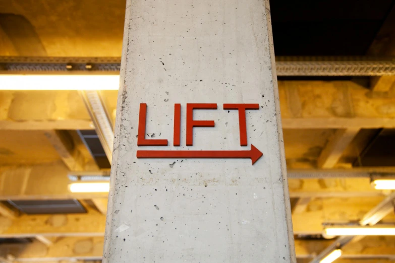 a red lift sign mounted to the side of a cement pillar, by Daniel Lieske, unsplash, lifting weights, picture of an interior loft, lut, looking up