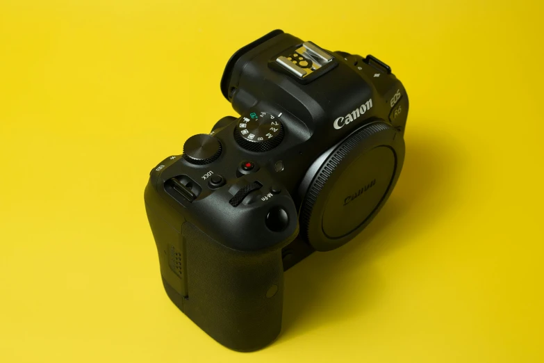 a camera sitting on top of a yellow surface, a portrait, canon on chest, high quality product photography, photography]