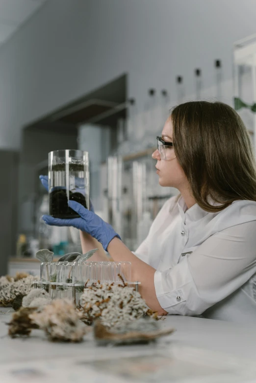 a woman in white shirt and blue gloves holding a glass, pexels contest winner, ferrofluid oceans, research center, avatar image, deep black roots