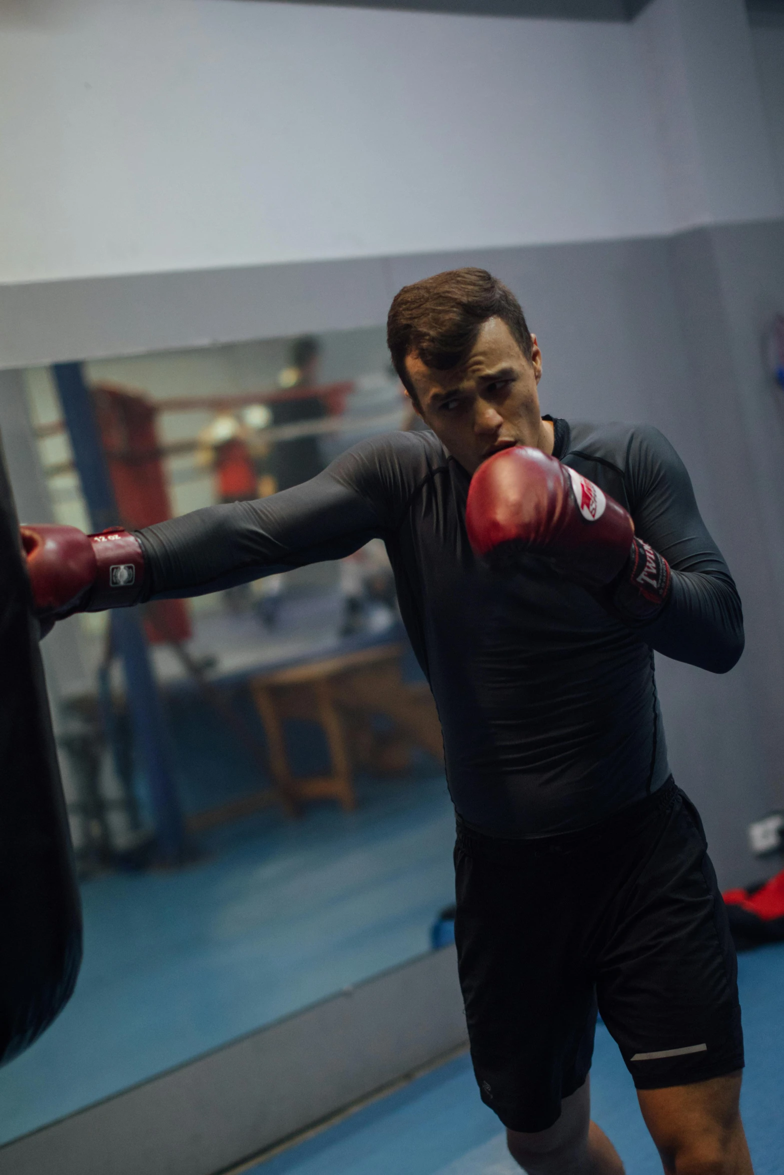 a man standing next to a punching bag, by Julian Allen, happening, charlie cox, sparring, square, anton fadeev 8 k