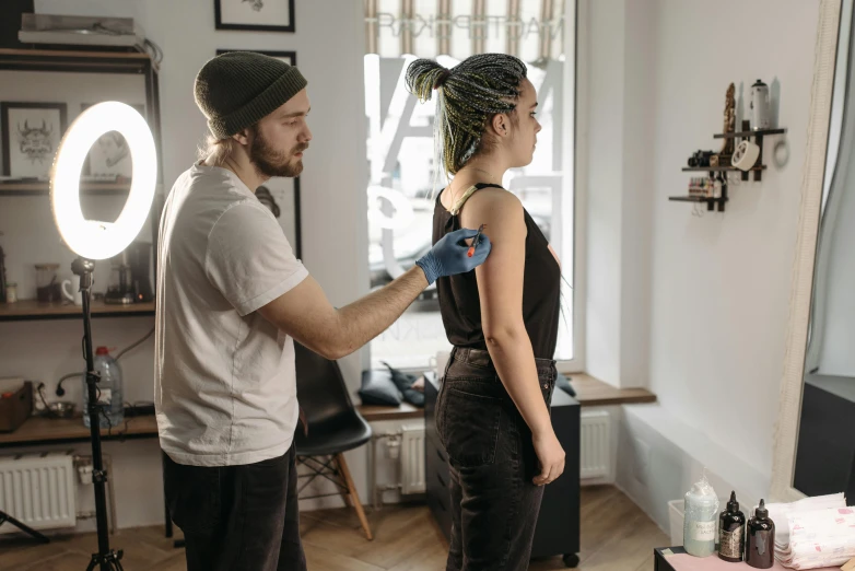 a man standing next to a woman in a room, a tattoo, pexels contest winner, acupuncture treatment, profile image, starving artist wearing overalls, upper body image