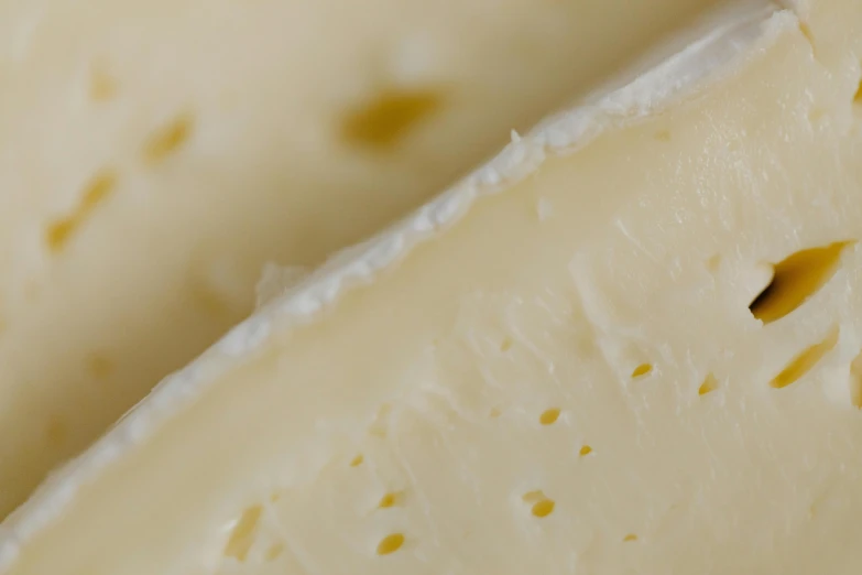 a close up of a piece of cheese, by Tom Bonson, unsplash, creamy, high angle close up shot, thin dof, vanilla