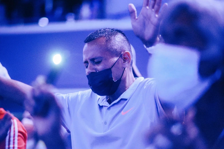 a man wearing a face mask with his hands in the air, les nabis, blue haze, ronaldo nazario, many people worshipping, profile image