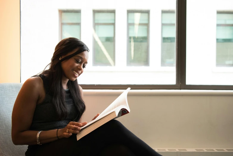 a woman sitting on a couch reading a book, academic art, dark skinned, profile image, sat in an office, multiple stories