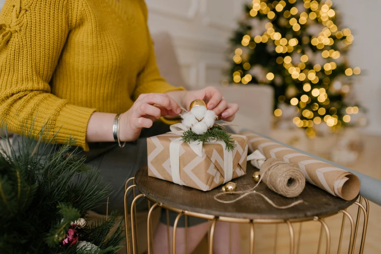 a woman wrapping presents on a table in front of a christmas tree, by Julia Pishtar, white and yellow scheme, fan favorite, medium closeup, posed