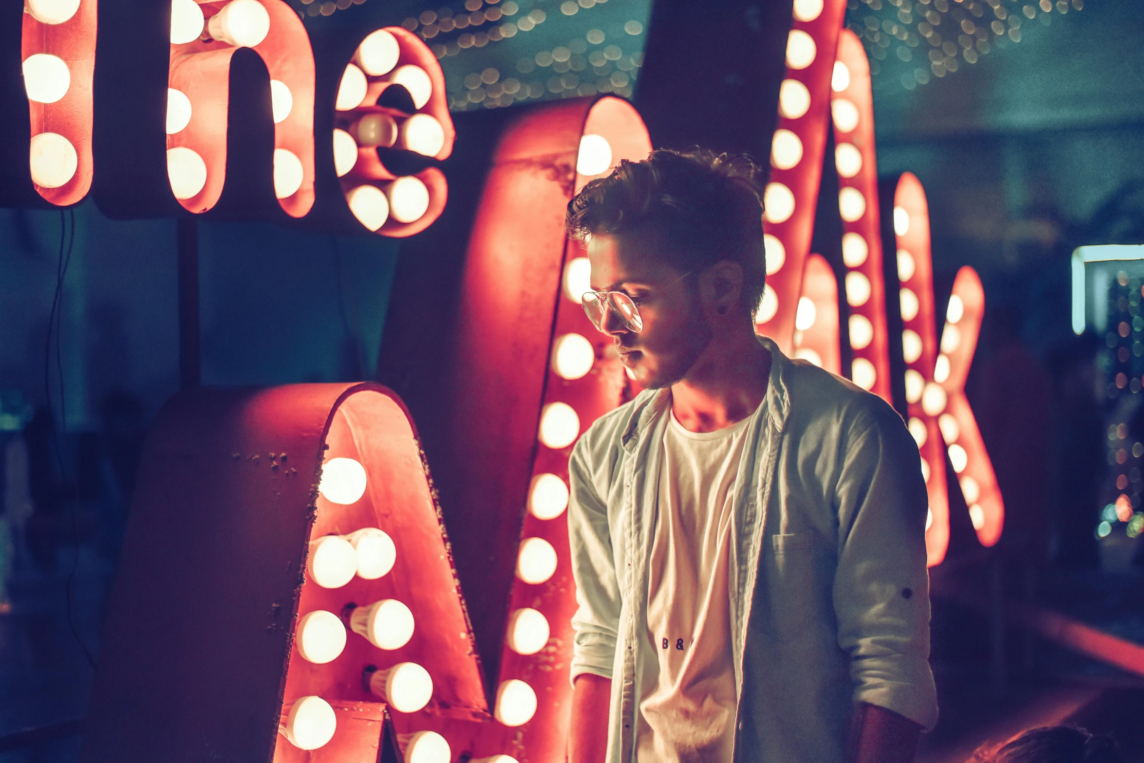 a man standing in front of a neon sign, pexels contest winner, shia labeouf, zayn malik, dreamy scene, retro lights