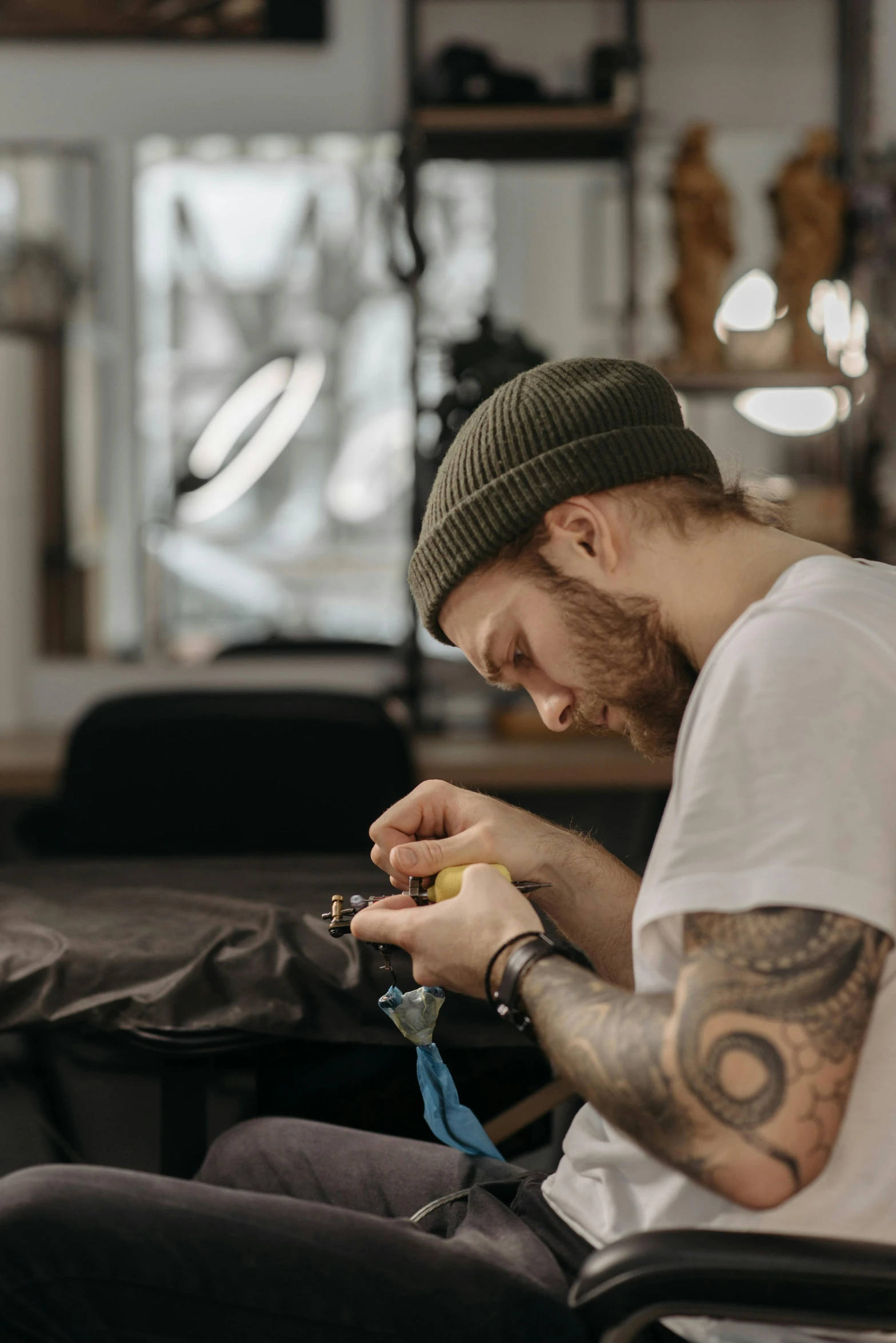 a man sitting in a chair with a tattoo on his arm, trending on pexels, stitching, artist wearing overalls, carving, lightweight