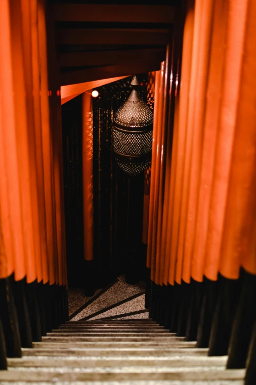 a set of stairs going up to the top of a building, by Micha Klein, unsplash, orange lights, beaded curtains, in a hotel hallway, black and terracotta