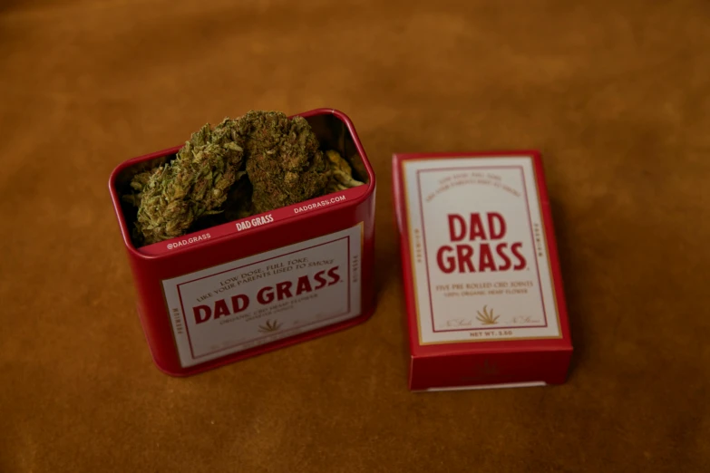 a box of weed sitting next to a box of dad grass, by Julia Pishtar, metal lid, red grass, detailed product image, 0