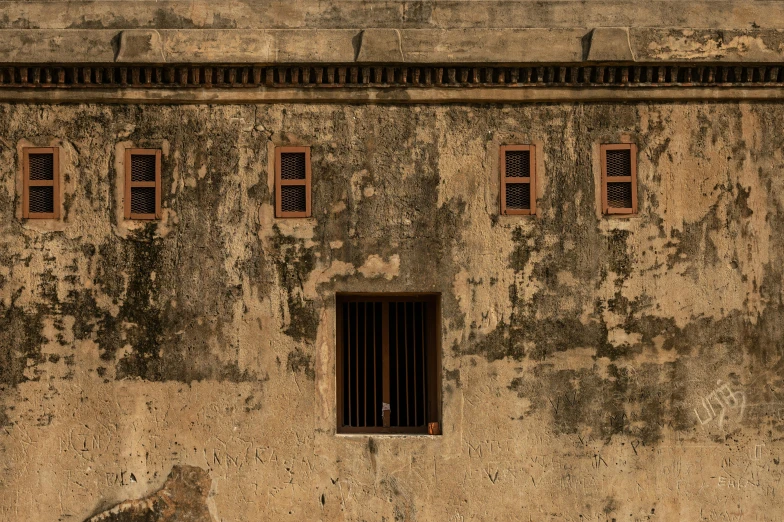 a man sitting on a bench in front of a building, an album cover, inspired by Steve McCurry, pexels contest winner, intricate textures, in a small prison cell, colonial exploration, minimalist photo