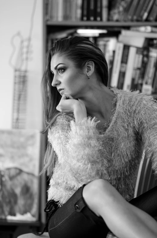a woman sitting on a chair in front of a book shelf, a black and white photo, inspired by Andrea Orcagna, glittering and soft, portrait of a beautiful model, wearing casual sweater, expressive!!!!!