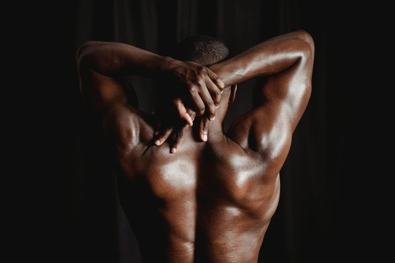 a man with his back to the camera, dark skin tone, rippling muscles, dark-toned product photos, in pain