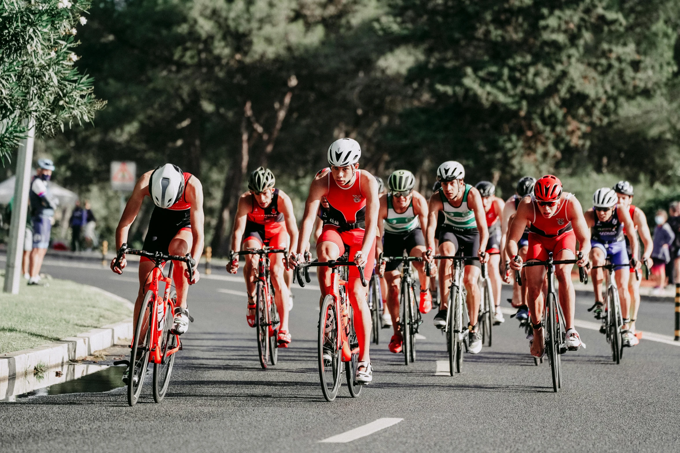 a group of bicyclists riding down a road, pexels contest winner, red sport clothing, sprinters in a race, sleeveless, promo image