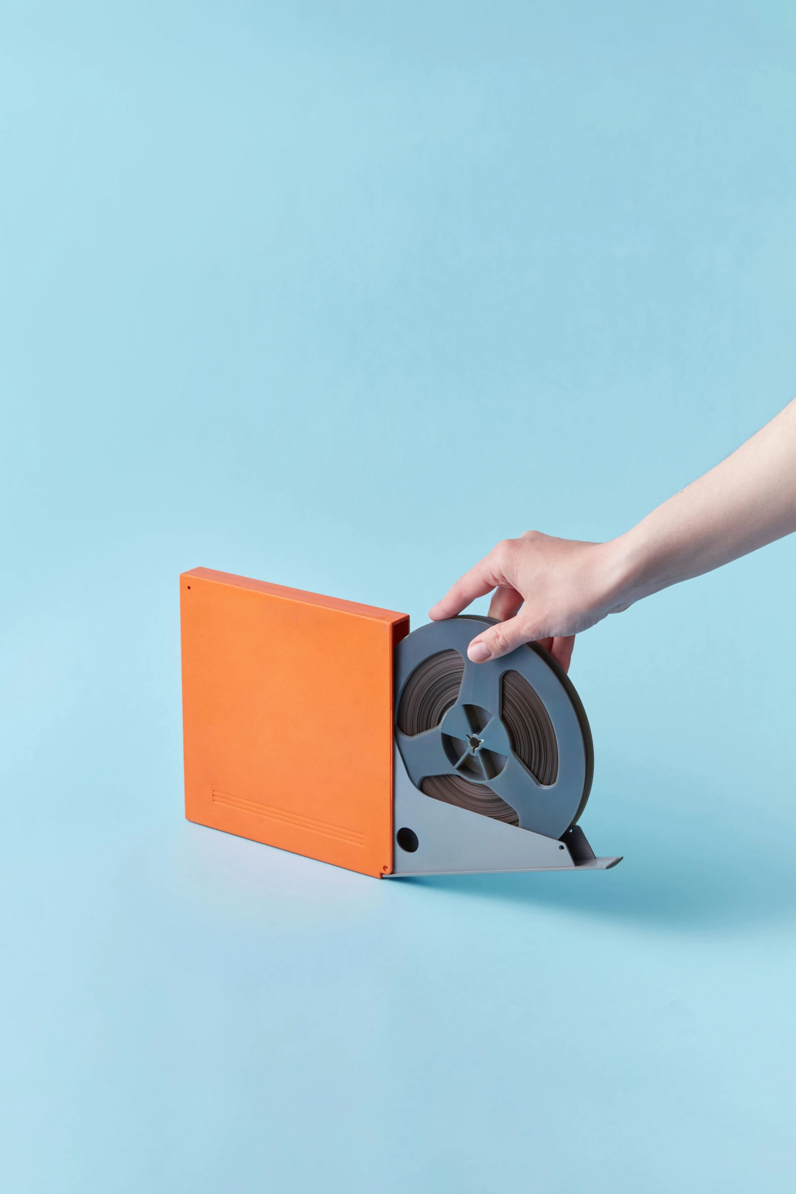 a person holding a reel on a blue background, an album cover, by jeonseok lee, unsplash, video art, orange color tone, in the original box, up-angle view, blu - ray transfer 5 k