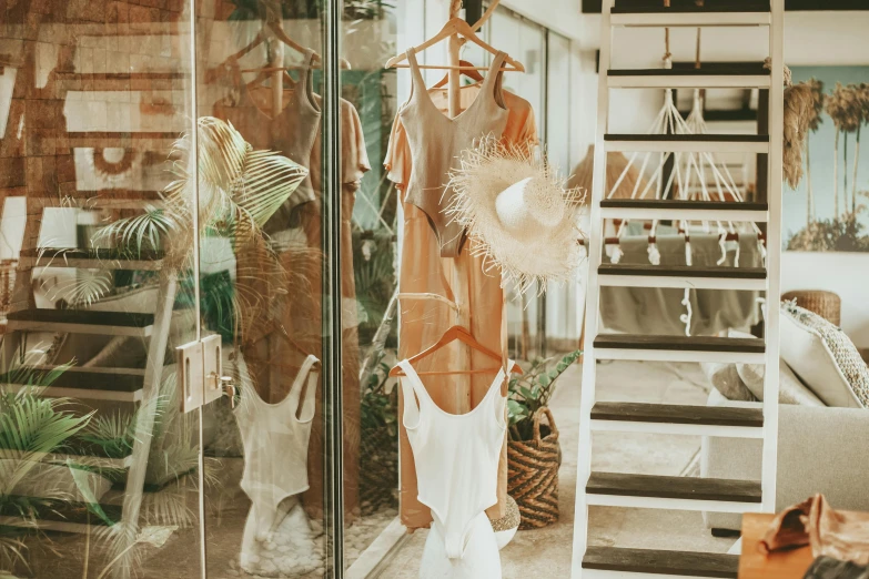 a dress hanging on a hanger in a room, unsplash, gold transparent bikini, shop front, nature outside, brown and white color scheme