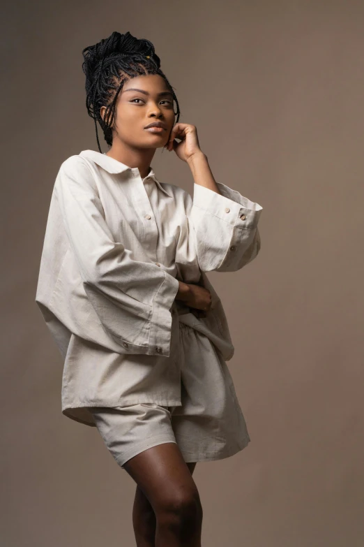 a woman in a white shirt and shorts posing for a picture, an album cover, by Chinwe Chukwuogo-Roy, trending on pexels, renaissance, cropped wide sleeve, beige, studio photoshot, long shirt