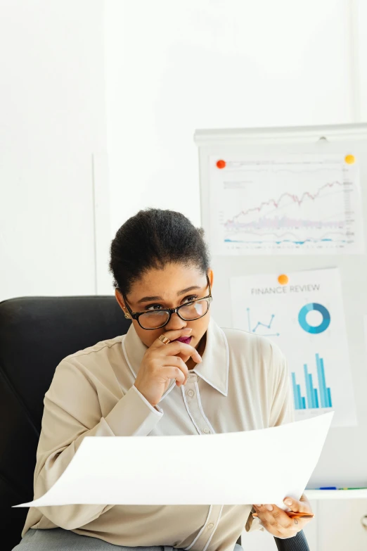 a woman sitting at a desk with papers in front of her, a cartoon, trending on unsplash, looking confused, graphs, low quality photo, typical cryptocurrency nerd