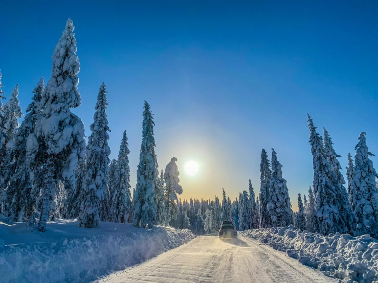 a car driving down a snow covered road, by Anton Lehmden, pexels contest winner, romanticism, sunny day with clear sky, 🌲🌌, tree-lined path at sunset, thumbnail