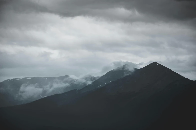 a black and white photo of a mountain range, pexels contest winner, minimalism, dark storm clouds, somber colors, whistler, cinematic 4k wallpaper