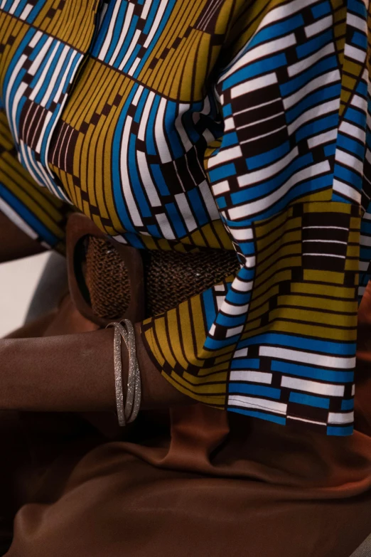 a close up of a person holding a cell phone, by Ingrida Kadaka, happening, patterned clothing, brown, slide show, blues