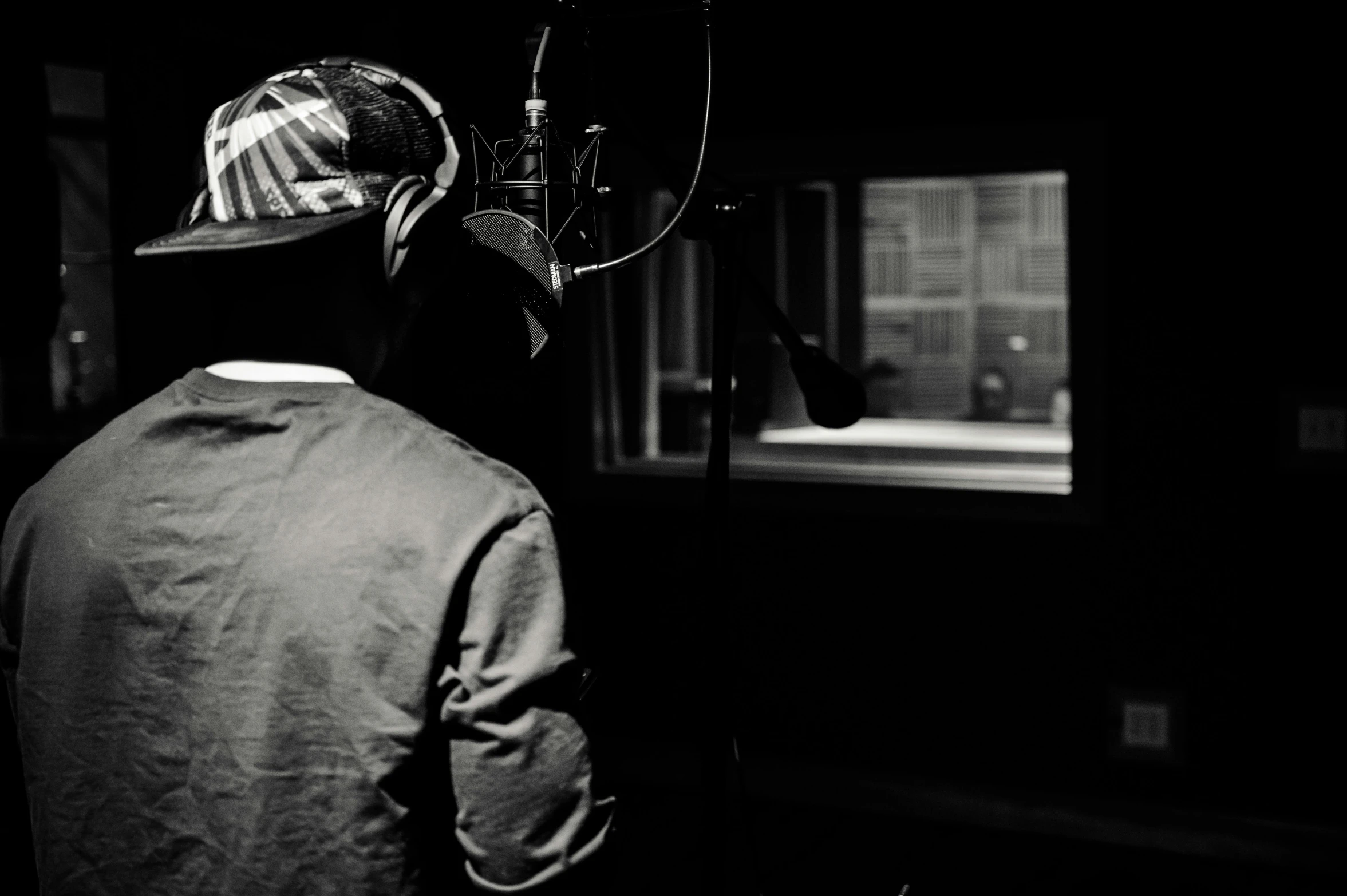 a black and white photo of a man in a recording studio, an album cover, pexels, process art, hip-hop, backfacing, looking outside, shot on sony a 7