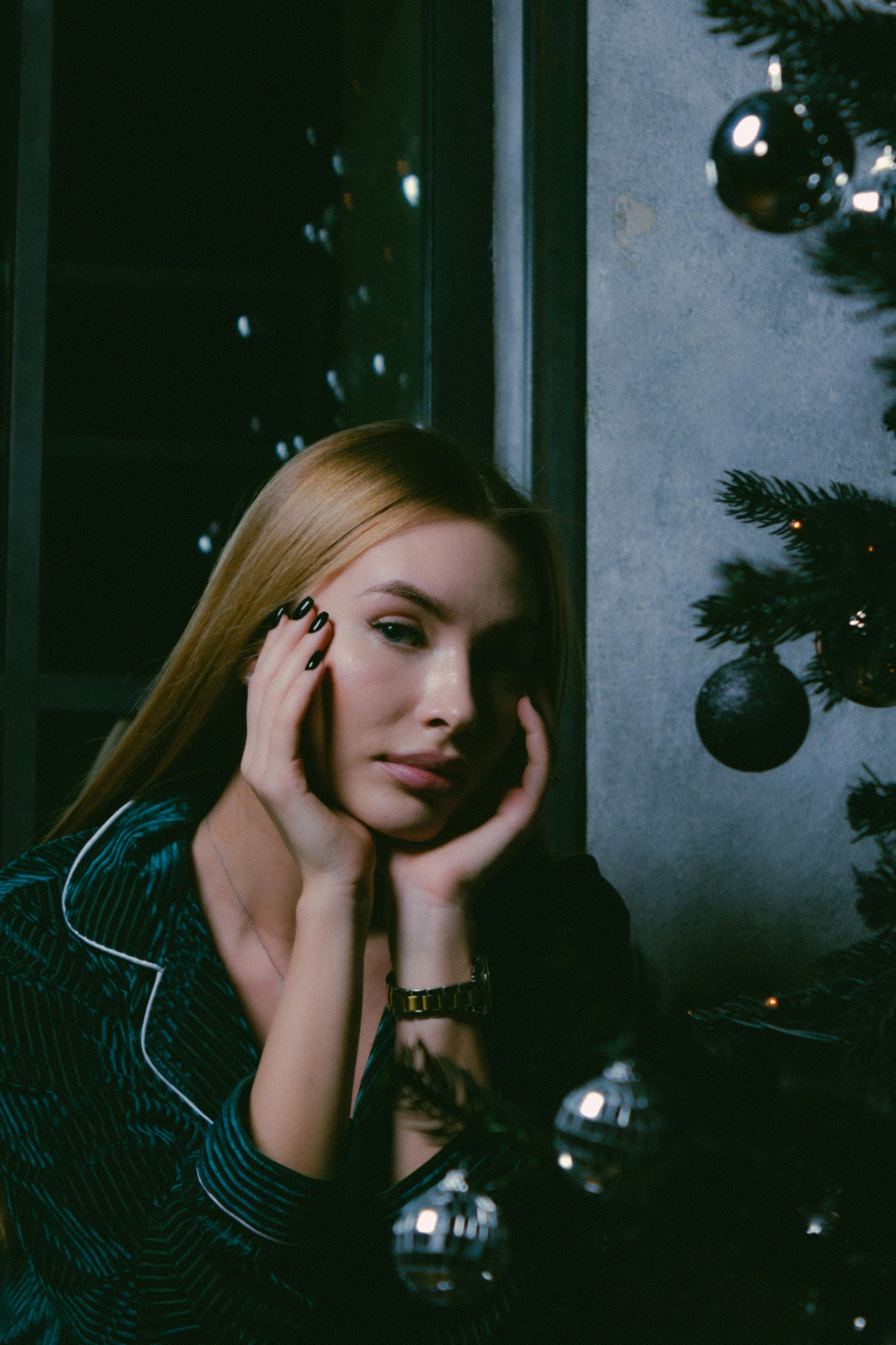 a woman sitting in front of a christmas tree, inspired by Elsa Bleda, trending on pexels, realism, sleepy fashion model face, sleek, midnight, instagram post