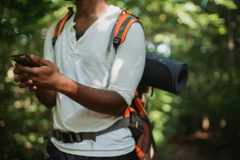 a man standing in the woods looking at his cell phone, trending on pexels, figuration libre, technical vest, dark-skinned, pictured from the shoulders up, holding a stuff