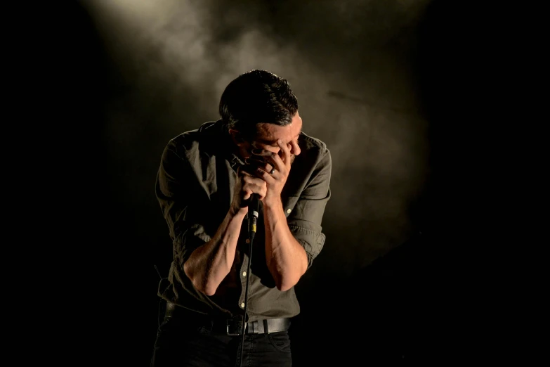 a man that is standing in front of a microphone, an album cover, pexels, antipodeans, head bowed slightly, concert, hand over mouth, luke evans