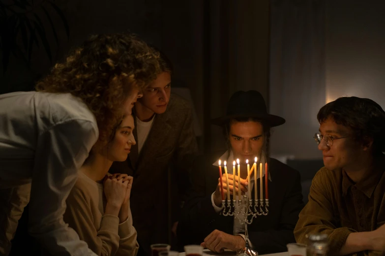 a group of people sitting around a table with a menorah, movie still 8 k, joe keery, cinestill hasselblad 8 5 mm, kramskoi 4 k