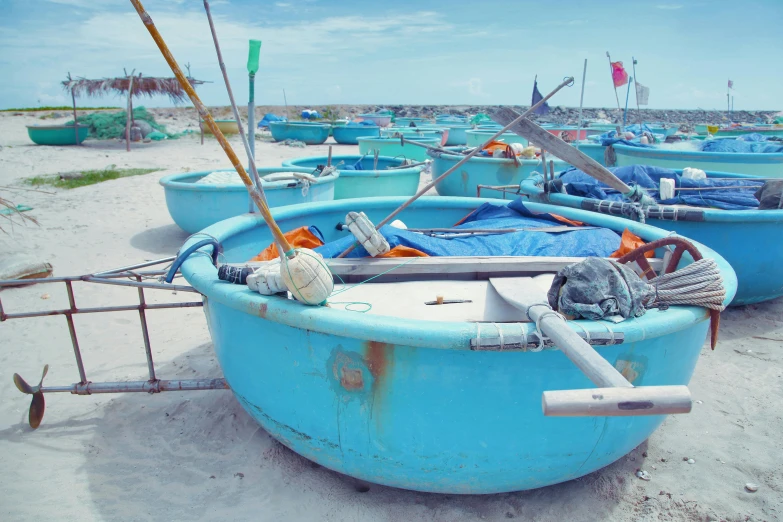 a group of blue boats sitting on top of a sandy beach, pexels contest winner, plasticien, vietnam, bowl, hdpe, grey