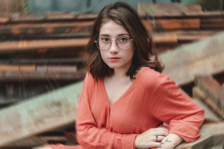 a woman sitting on top of a wooden bench, a portrait, inspired by Elsa Bleda, pexels contest winner, hyperrealism, square rimmed glasses, coral brown hair, high quality image, 18 years old