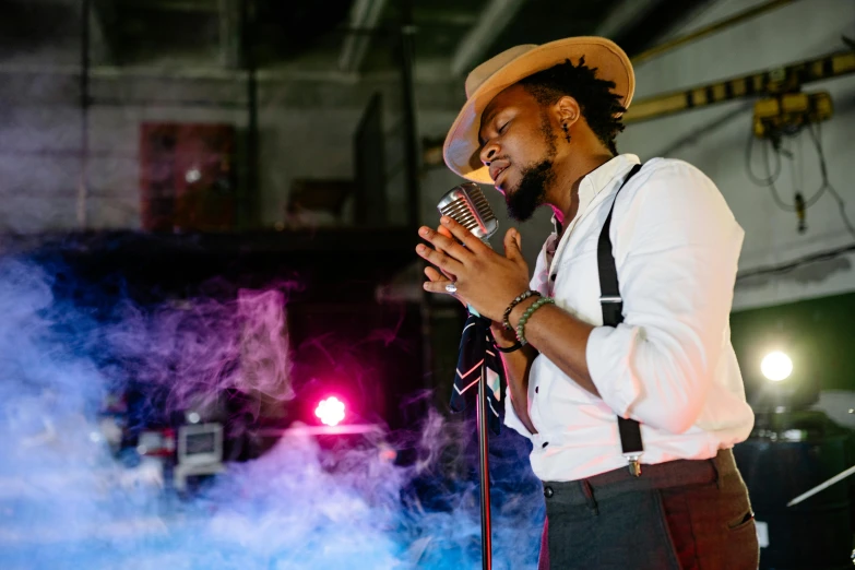 a man in a hat singing into a microphone, pexels, lyco art, essence, thumbnail, high quality upload, pr shoot
