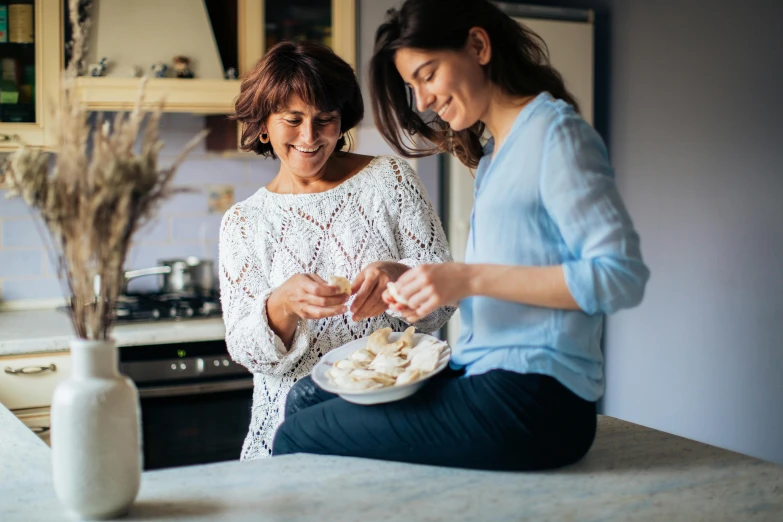 a couple of women sitting on top of a kitchen counter, by Arabella Rankin, pexels contest winner, dumplings on a plate, manuka, older woman, family friendly