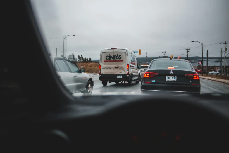 a couple of cars driving down a street, by Chris Rallis, pexels contest winner, traffic accident, grey skies, 🚿🗝📝, people at work