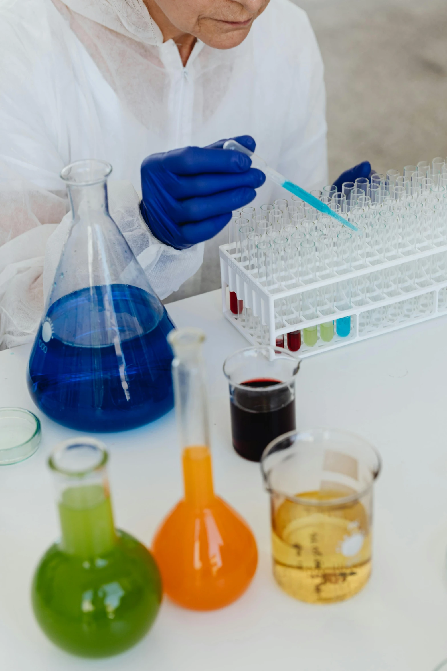 a woman in a lab coat working in a laboratory, pexels, analytical art, rainbow liquids, gloves on hands, on a white table, medical labels