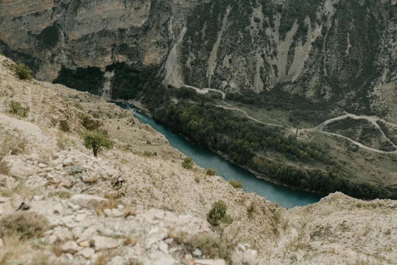 a man standing on top of a mountain next to a river, pexels contest winner, les nabis, high view, thumbnail, steep cliffs, ash thorp khyzyl saleem