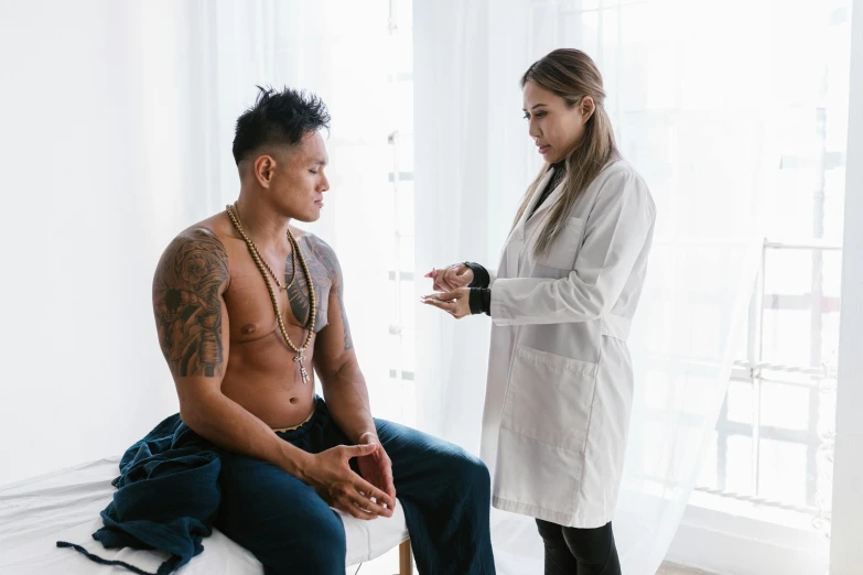 a man sitting on top of a bed next to a woman, a tattoo, pexels contest winner, male physician, damien tran, open v chest clothes, (doctor)