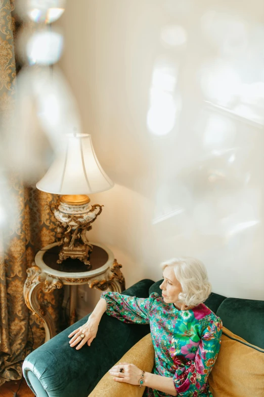 a woman sitting on a couch in a living room, a portrait, by Winona Nelson, trending on pexels, baroque, white hair floating in air, emerging from her lamp, inside a grand ornate room, flat lay