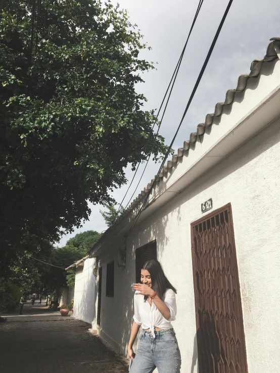 a woman walking down a street next to a building, breakfast at las pozas, is ((drinking a cup of tea)), 🤠 using a 🖥, mingchen shen